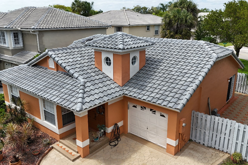 Orange stucco house with gray tiled roof, front porch, and a white two-car garage.