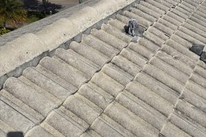 Grey concrete roof tiles with a small vent pipe near the center of the image and a shadow on the tiles