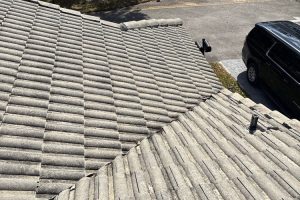 Two gray tiled roofs seen from above, with a parked dark SUV to the right.